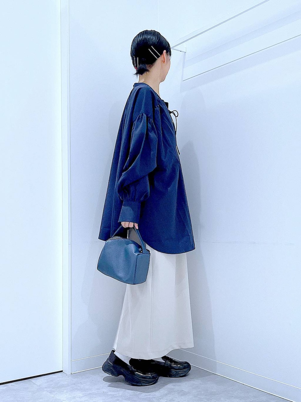 ベージュ系のスカート、ブラック系のローファー、ブルー系のショルダーバッグを着用したレディースの秋コーディネートの4枚目の写真