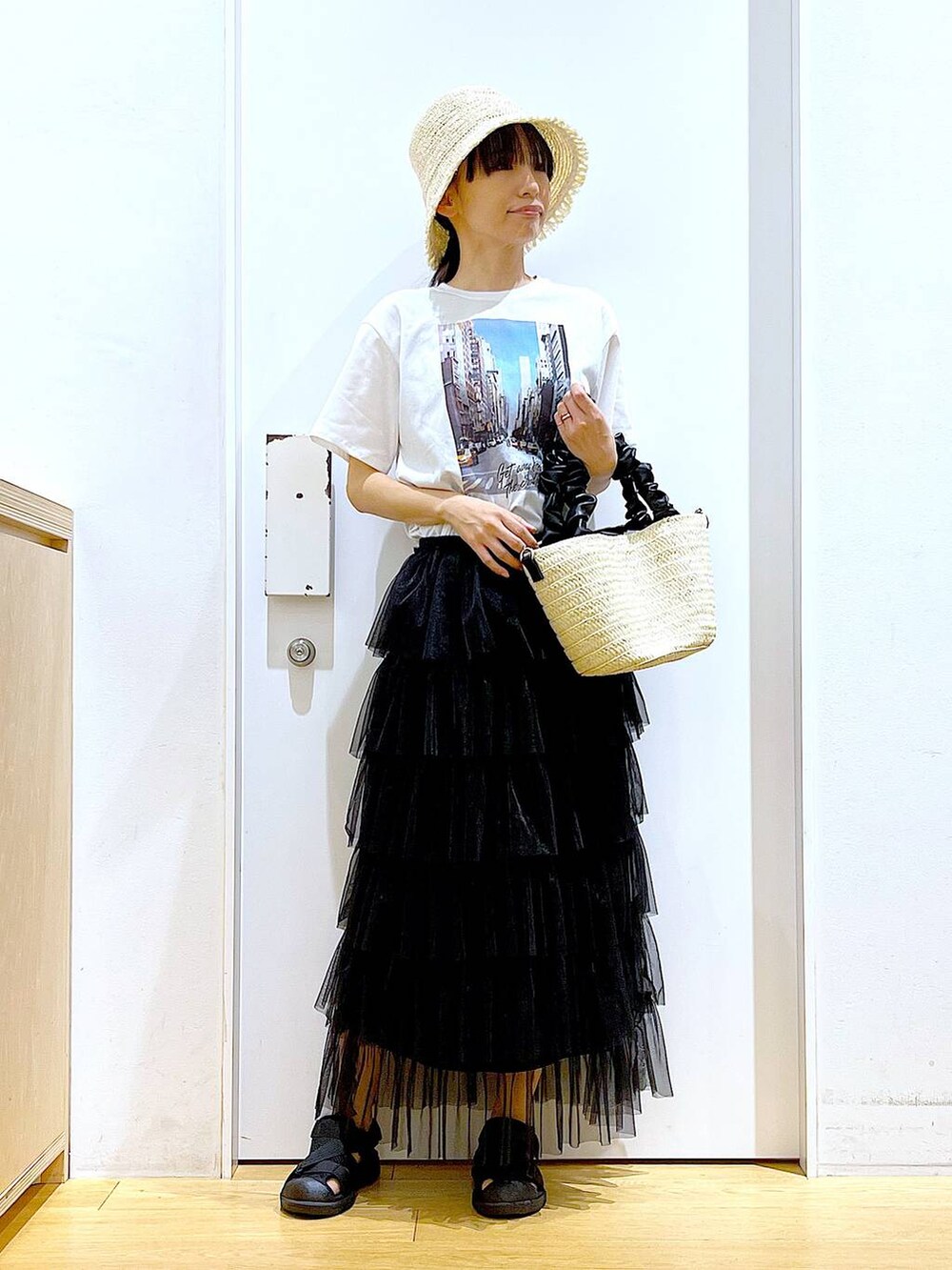 ホワイト系のショルダーバッグ、ブラック系のスリッポン、ブラック系のスカートを着用したレディースの夏コーディネートの2枚目の写真