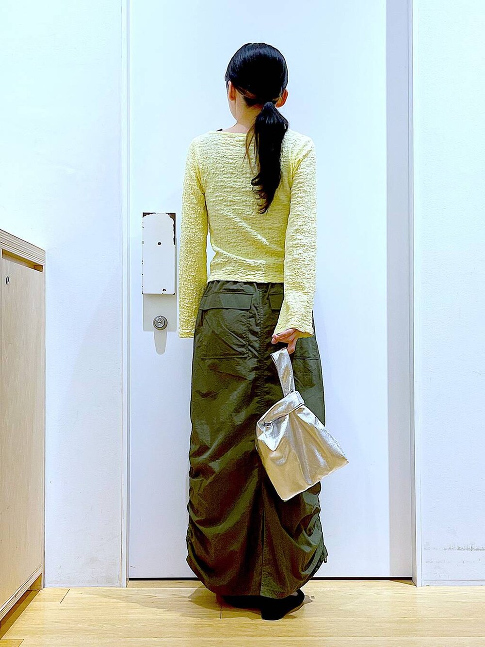 シルバー系のショルダーバッグ、グリーン系のスカート、ブラック系のパンプスを着用したレディースの春コーディネートの5枚目の写真