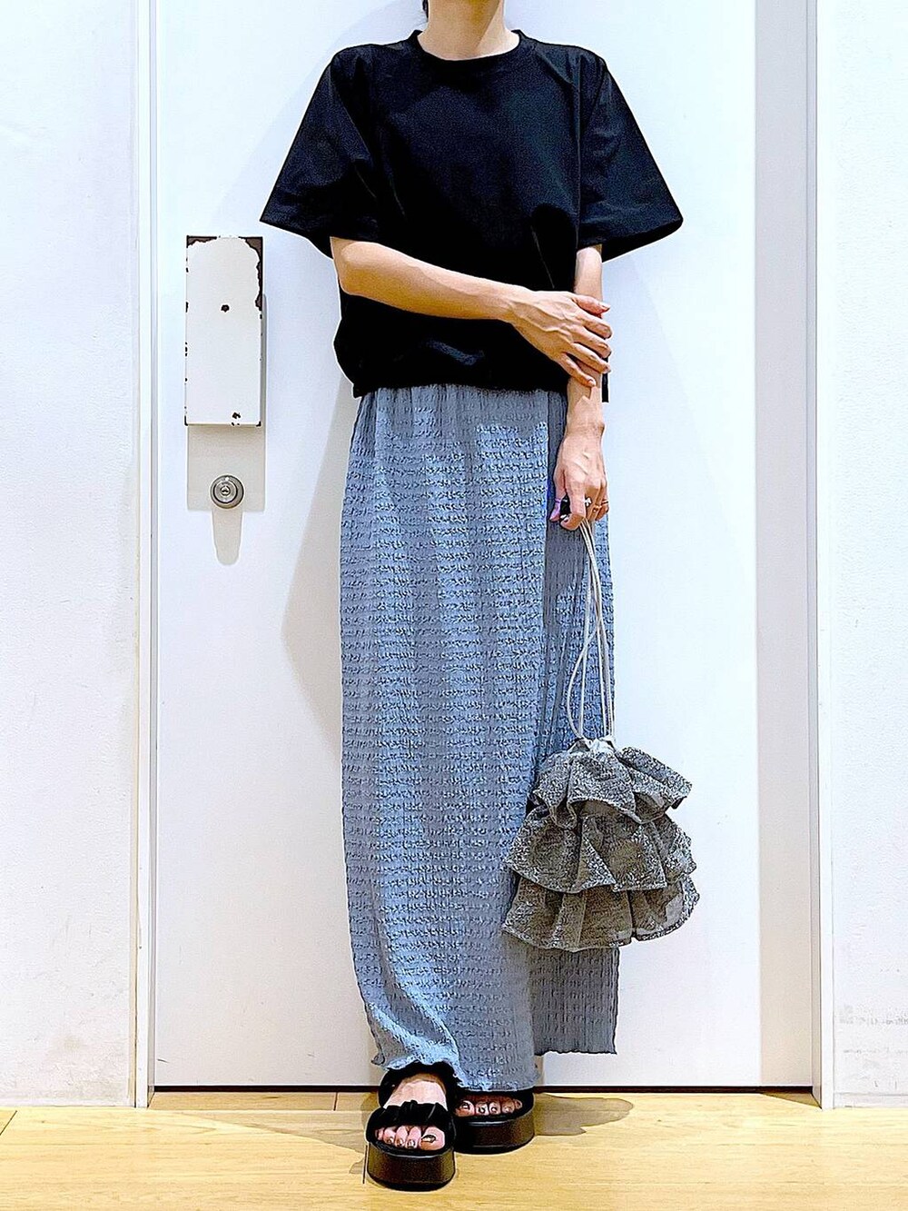 シルバー系のショルダーバッグ、ブルー系のスカート、ブラック系のTシャツ/カットソーを着用したレディースの夏コーディネートの6枚目の写真