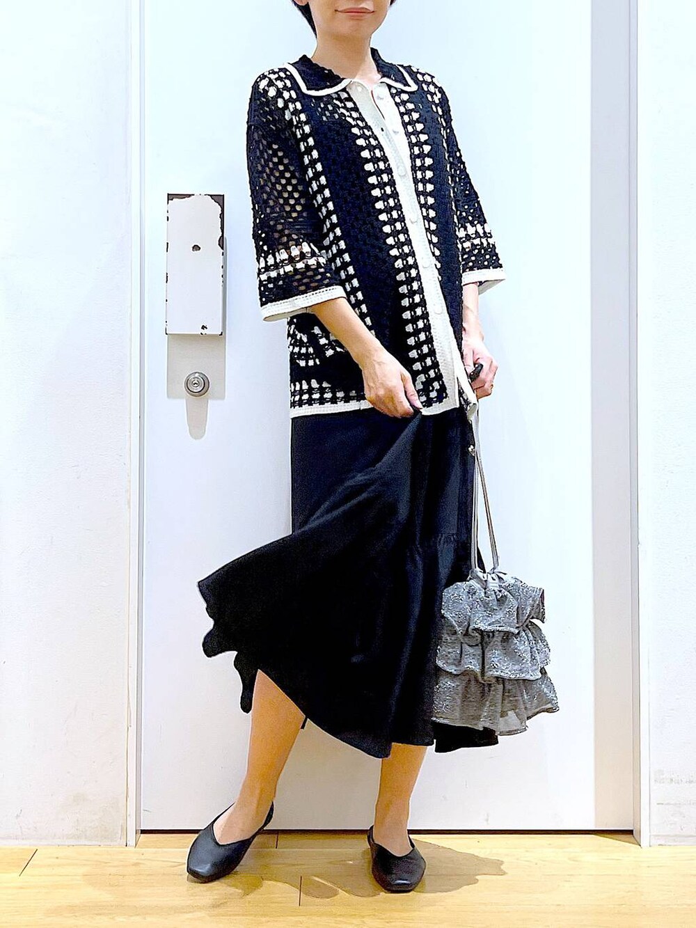 シルバー系のショルダーバッグ、ブラック系のパンプス、ブラック系のワンピースを着用したレディースの春コーディネートの6枚目の写真