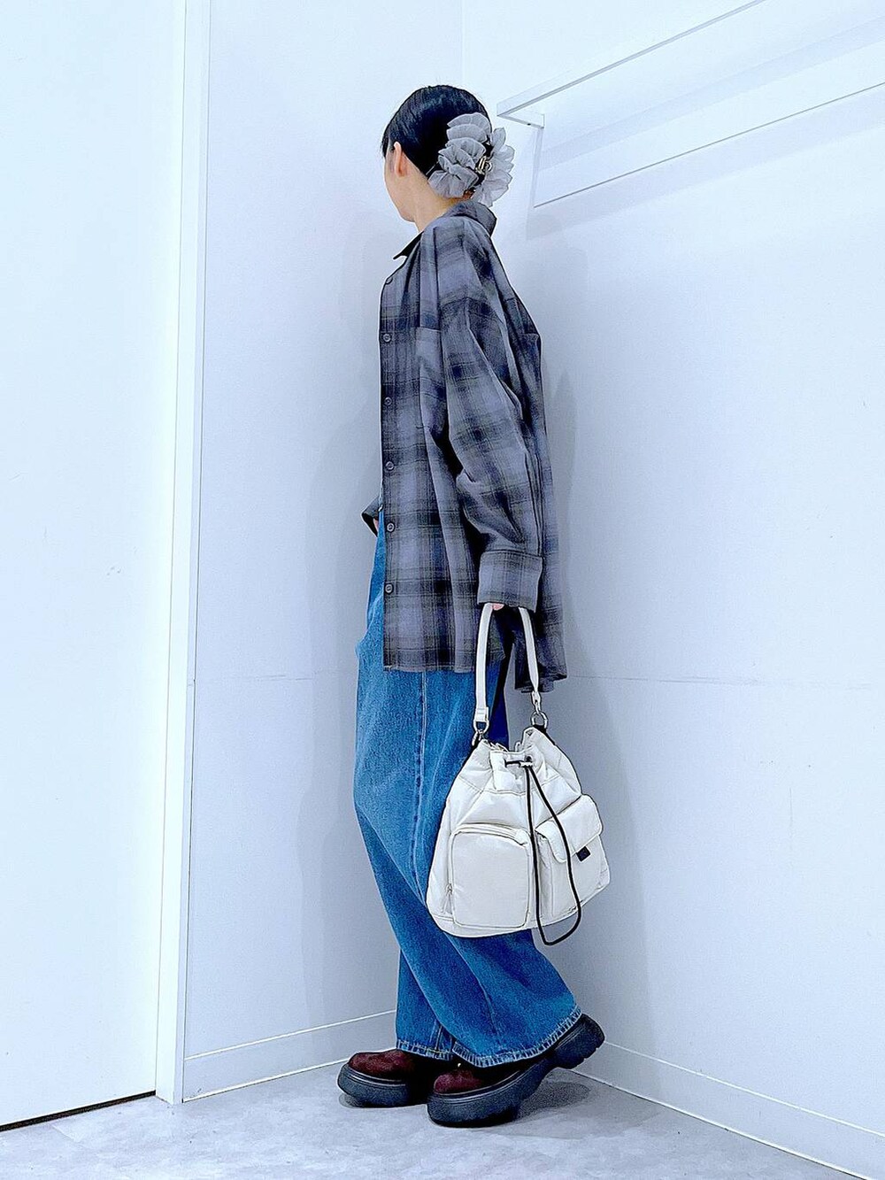 ブルー系のデニムパンツ、グレー系のシャツ/ブラウス、ホワイト系のハンドバッグを着用したレディースの秋コーディネートの3枚目の写真