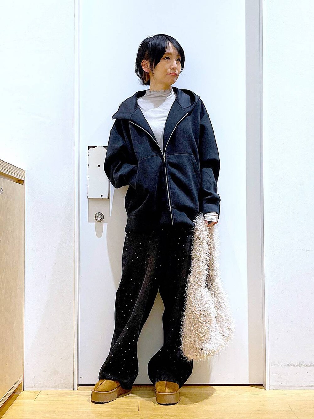 ベージュ系のスリッポン、ベージュ系のショルダーバッグ、ブラック系のデニムパンツを着用したレディースの冬コーディネートの2枚目の写真