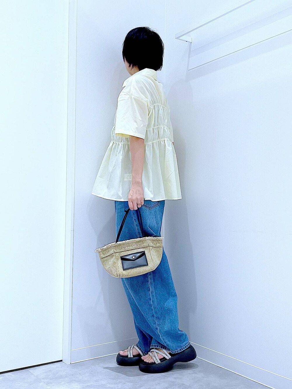 ブルー系のデニムパンツ、ベージュ系のショルダーバッグ、シルバー系のサンダルを着用したレディースの夏コーディネートの3枚目の写真