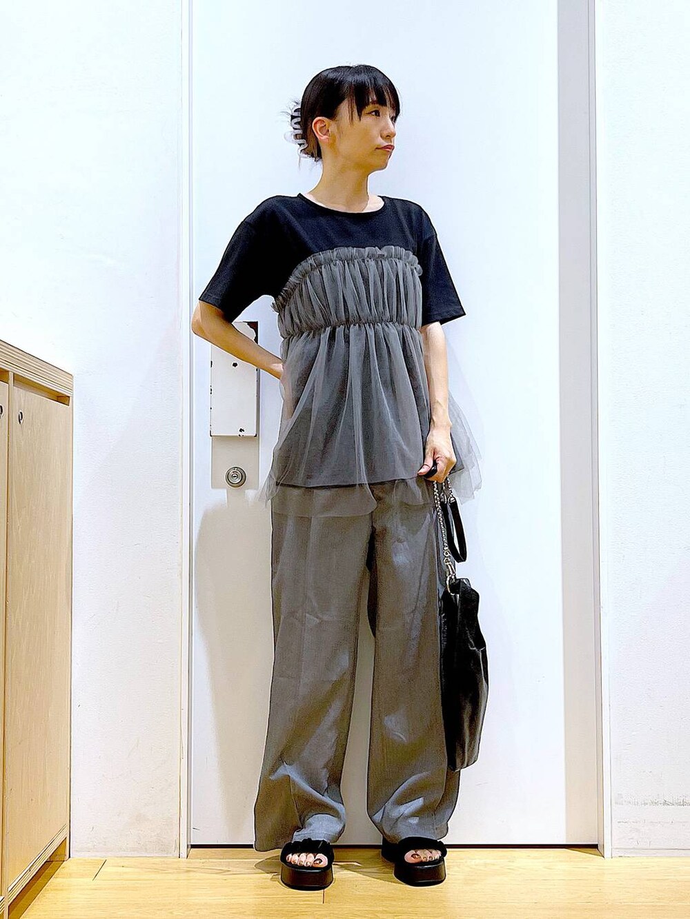 ブラック系のショルダーバッグ、ブラック系のサンダル、ブラック系のTシャツ/カットソーを着用したレディースの夏コーディネートの2枚目の写真