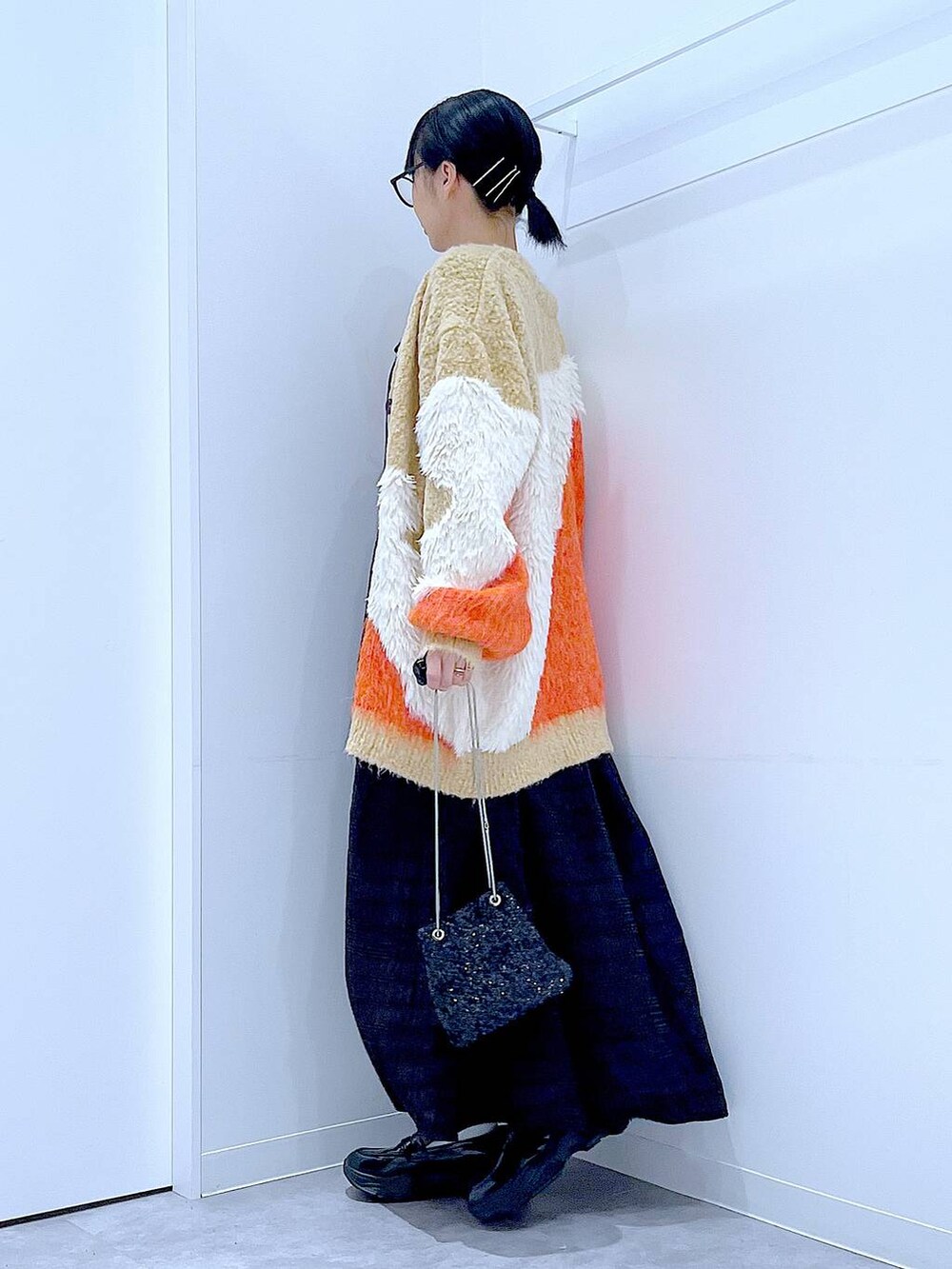 ブラック系のショルダーバッグ、ブラック系のローファー、オレンジ系のカーディガン/ボレロを着用したレディースの秋コーディネートの3枚目の写真