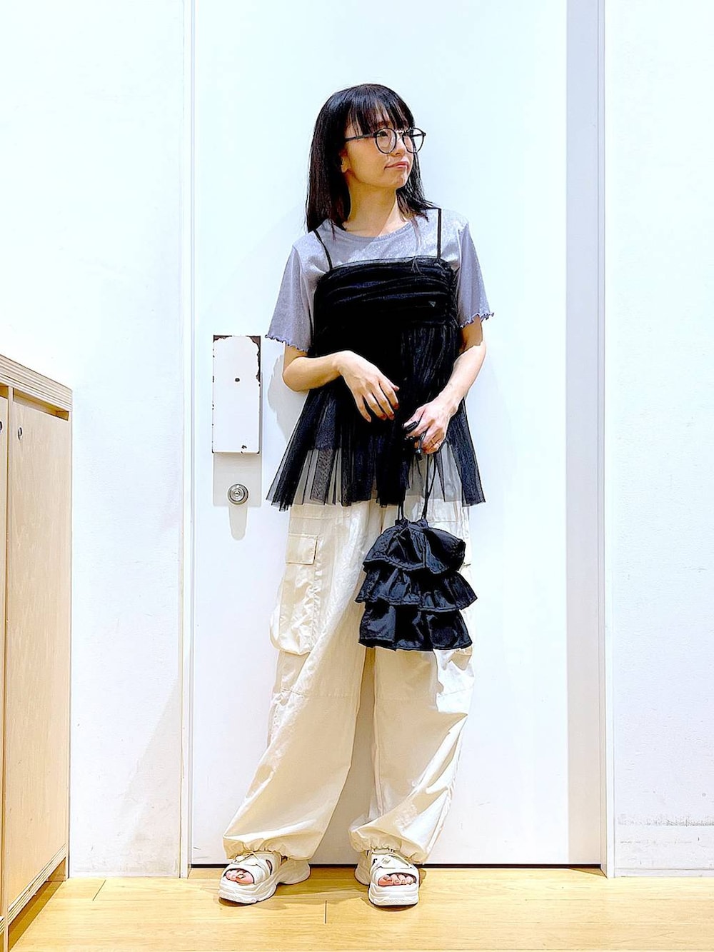 ブラック系のショルダーバッグ、ホワイト系のカーゴパンツ、ブラック系のキャミソールを着用したレディースの夏コーディネートの2枚目の写真