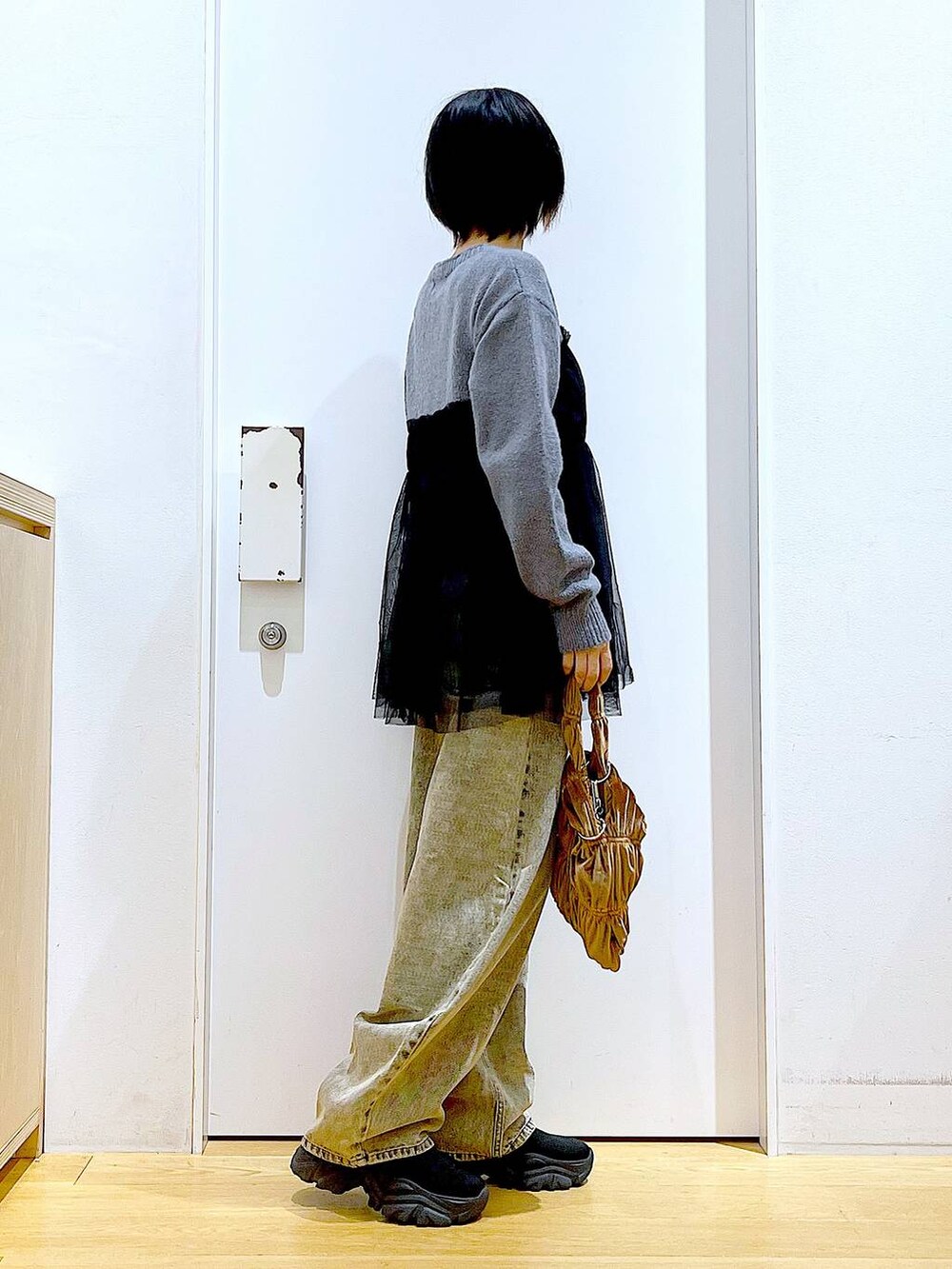 ブラック系のブーツ、イエロー系のショルダーバッグ、ベージュ系のデニムパンツを着用したレディースの秋コーディネートの4枚目の写真