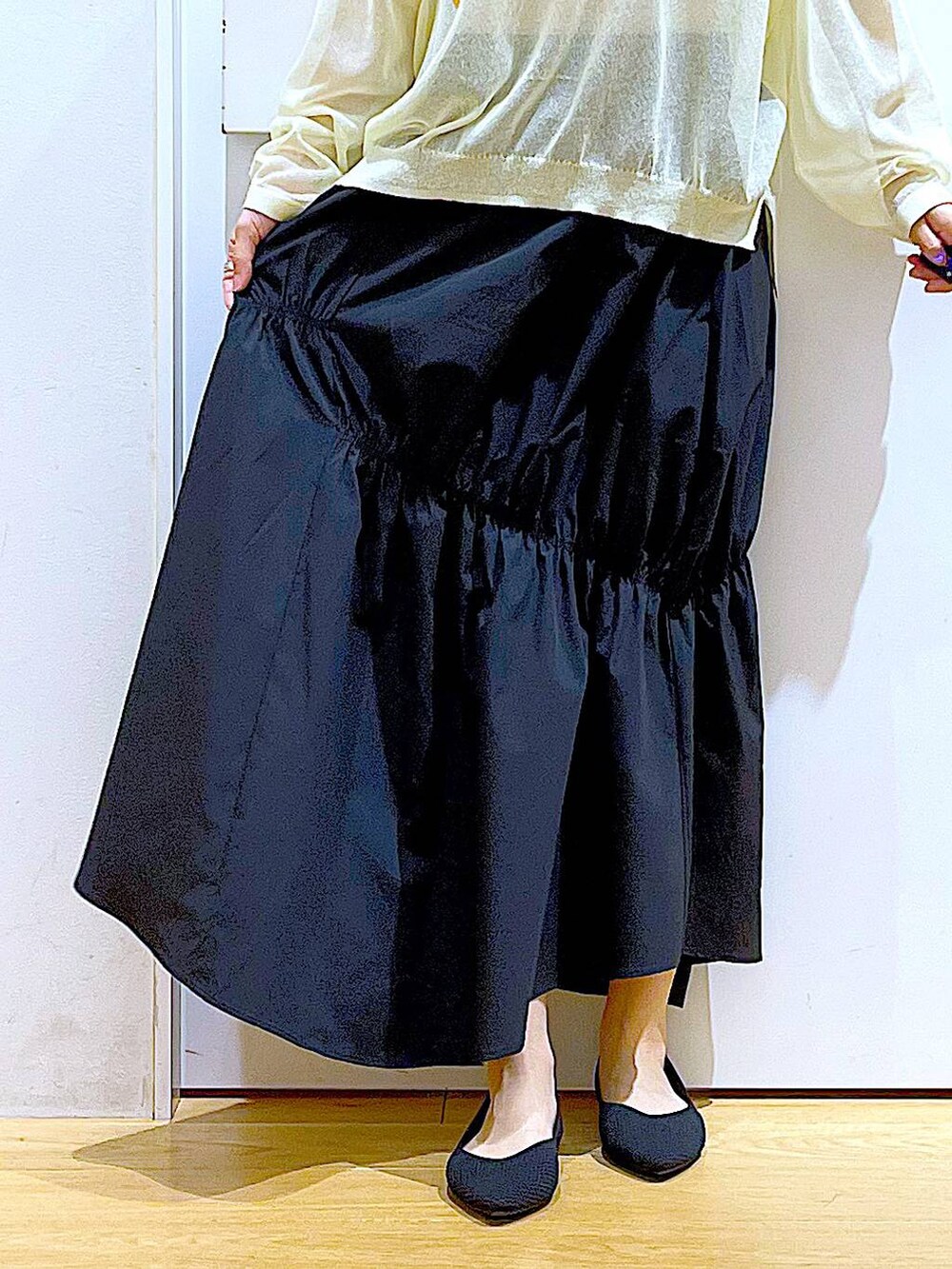 ホワイト系のニット/セーター、ブラック系のスカート、ブラック系のパンプスを着用したレディースの夏コーディネートの8枚目の写真