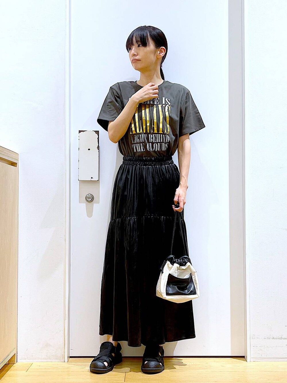 ホワイト系のショルダーバッグ、ブラック系のスリッポン、グレー系のTシャツ/カットソーを着用したレディースの夏コーディネートの2枚目の写真