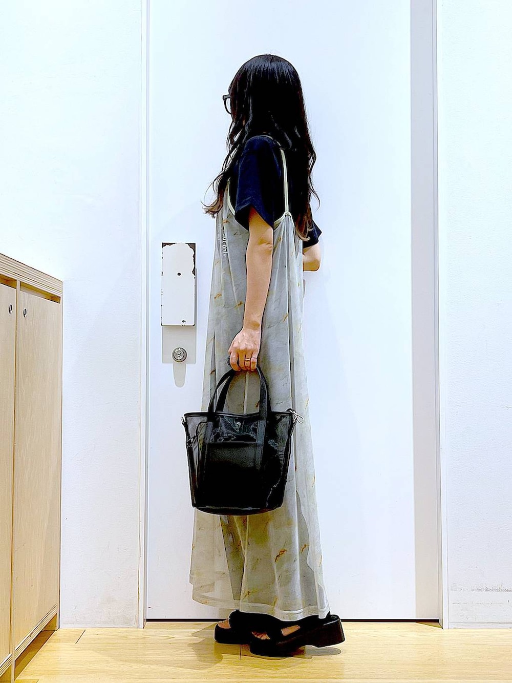 ブラック系のサンダル、ブラック系のトートバッグ、ベージュ系のワンピースを着用したレディースの夏コーディネートの3枚目の写真