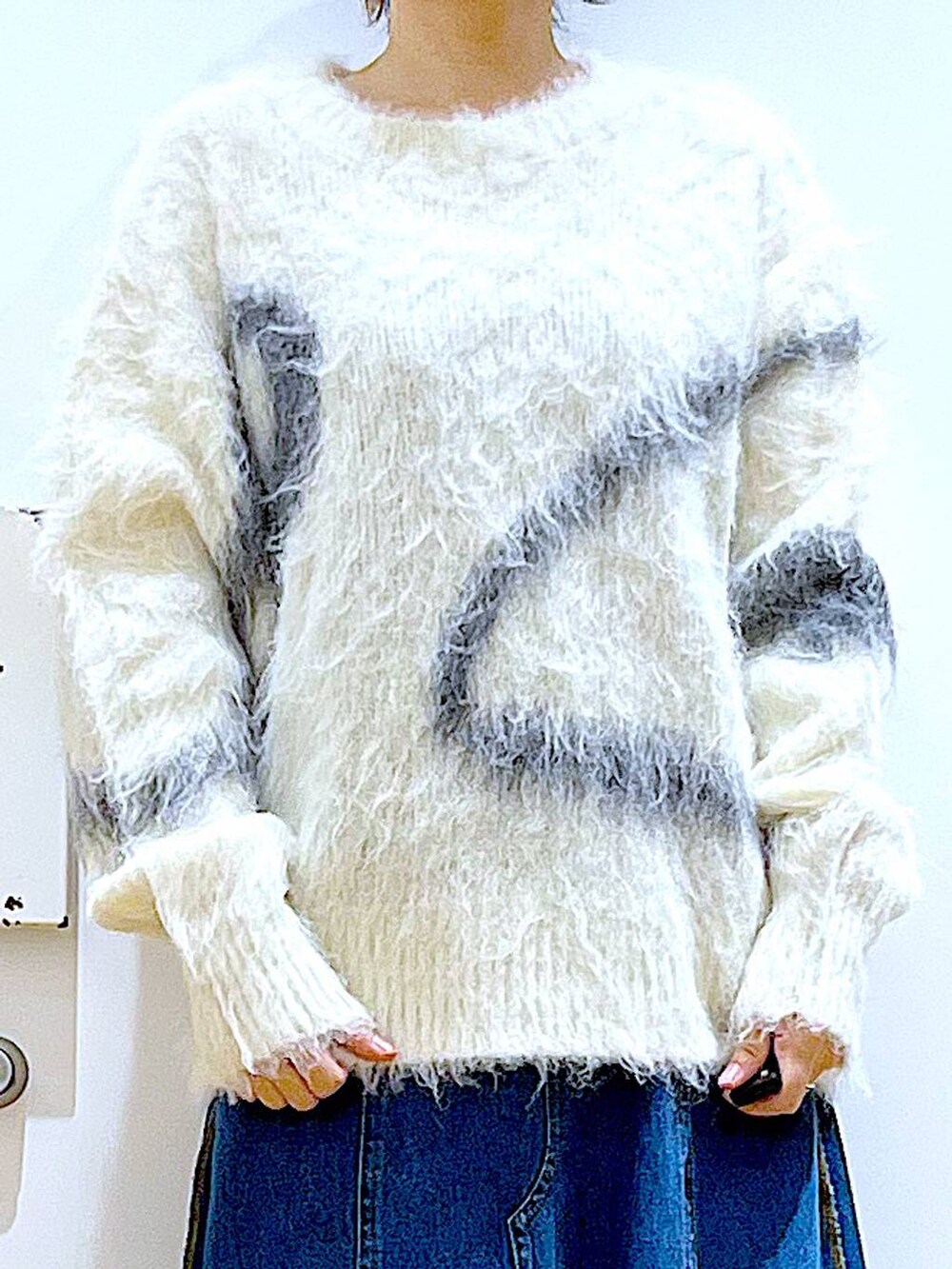 ホワイト系のニット/セーター、グレー系のバックパック/リュック、ブルー系のデニムスカートを着用したレディースの冬コーディネートの7枚目の写真