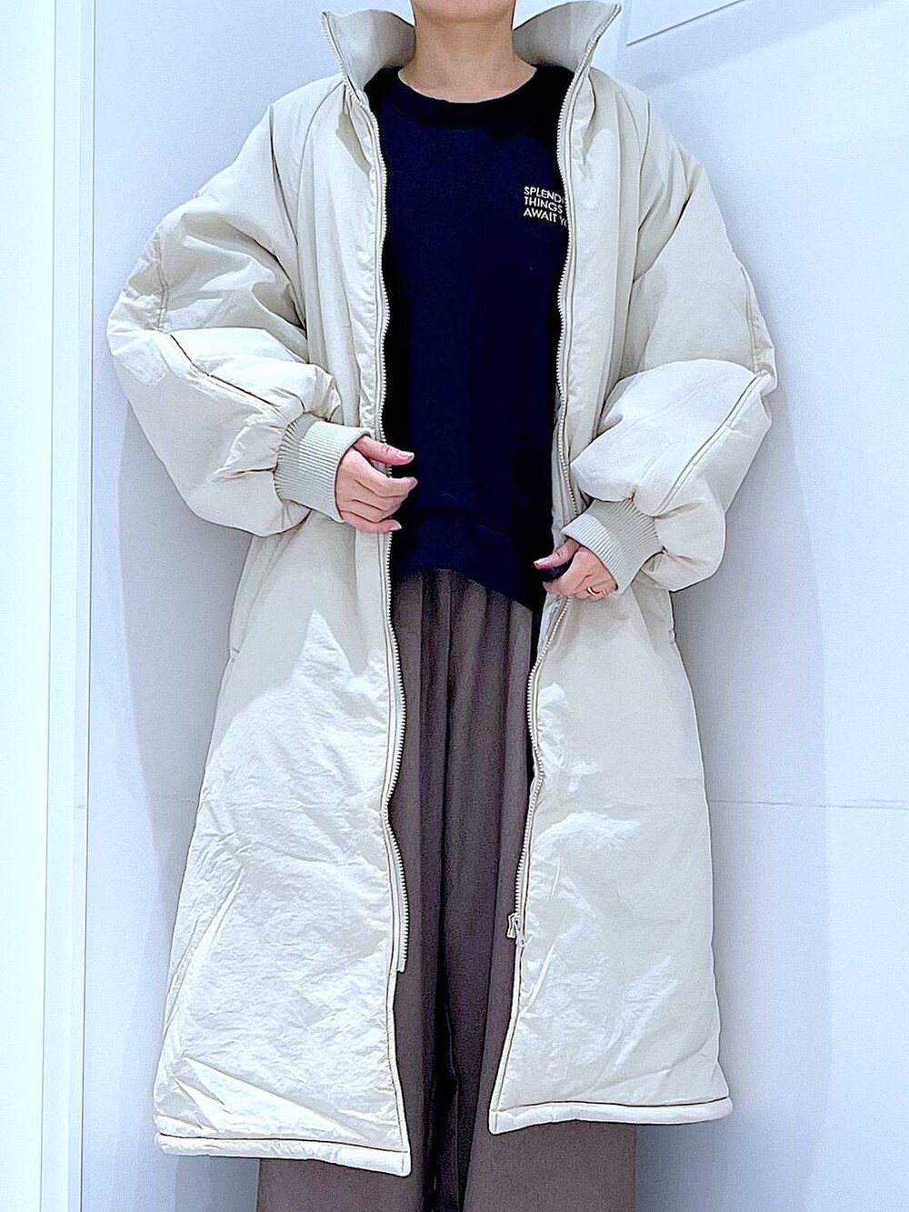 ホワイト系のブルゾン、ブラウン系のショルダーバッグ、ブラック系のブーツを着用したレディースの冬コーディネートの7枚目の写真