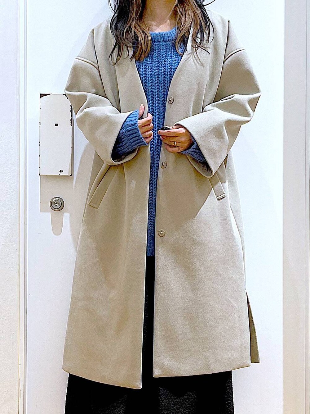 シルバー系のショルダーバッグ、ベージュ系のスニーカー、ベージュ系のノーカラーコートを着用したレディースの冬コーディネートの7枚目の写真