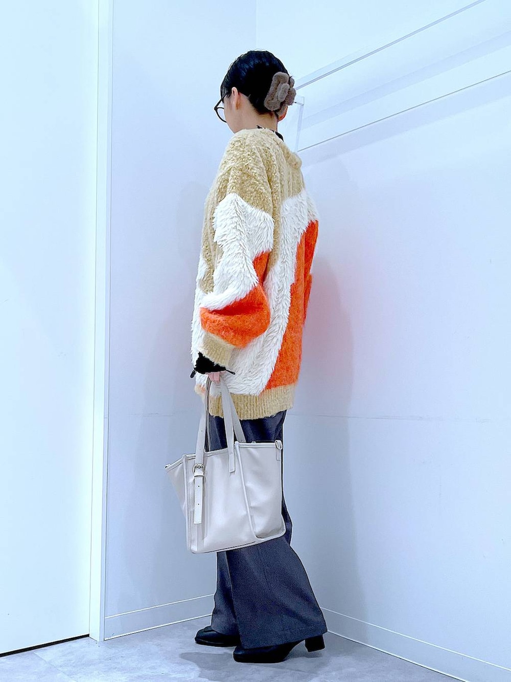 オレンジ系のカーディガン/ボレロ、ブラック系のブーツ、グレー系のスラックスを着用したレディースの冬コーディネートの3枚目の写真