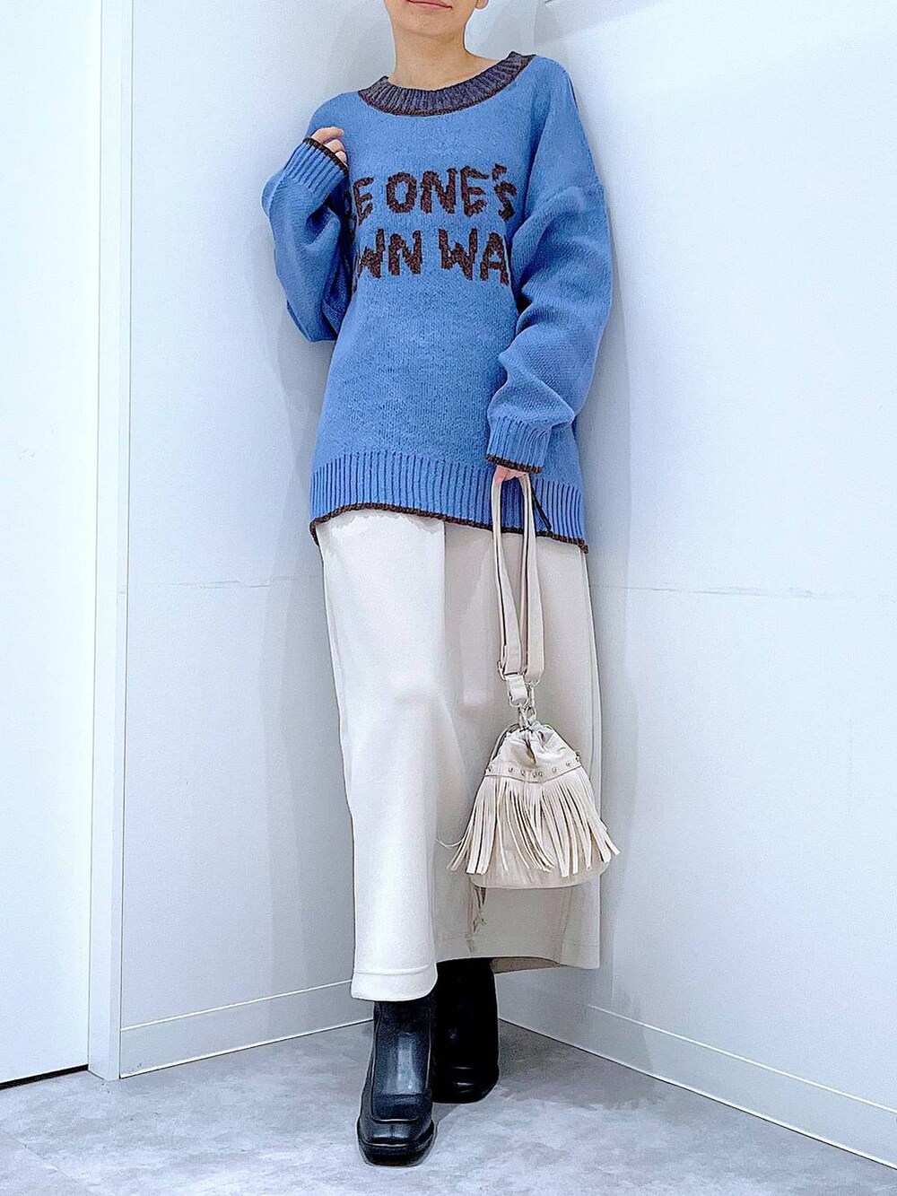 ベージュ系のスカート、ブラック系のブーツ、ホワイト系のショルダーバッグを着用したレディースの冬コーディネートの6枚目の写真