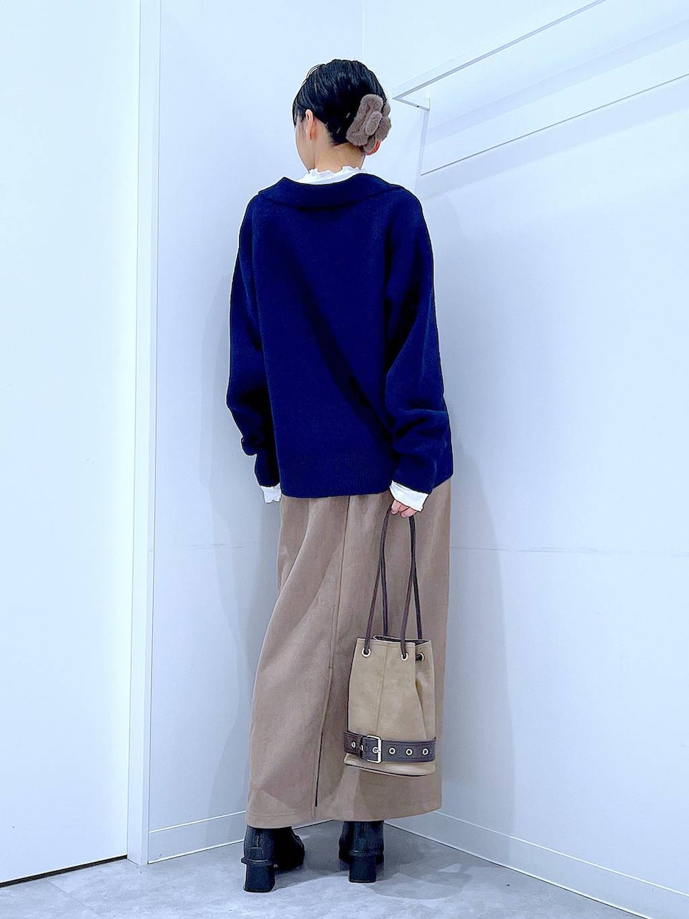 ブラック系のブーツ、ブラウン系のスカート、ベージュ系のハンドバッグを着用したレディースの冬コーディネートの5枚目の写真