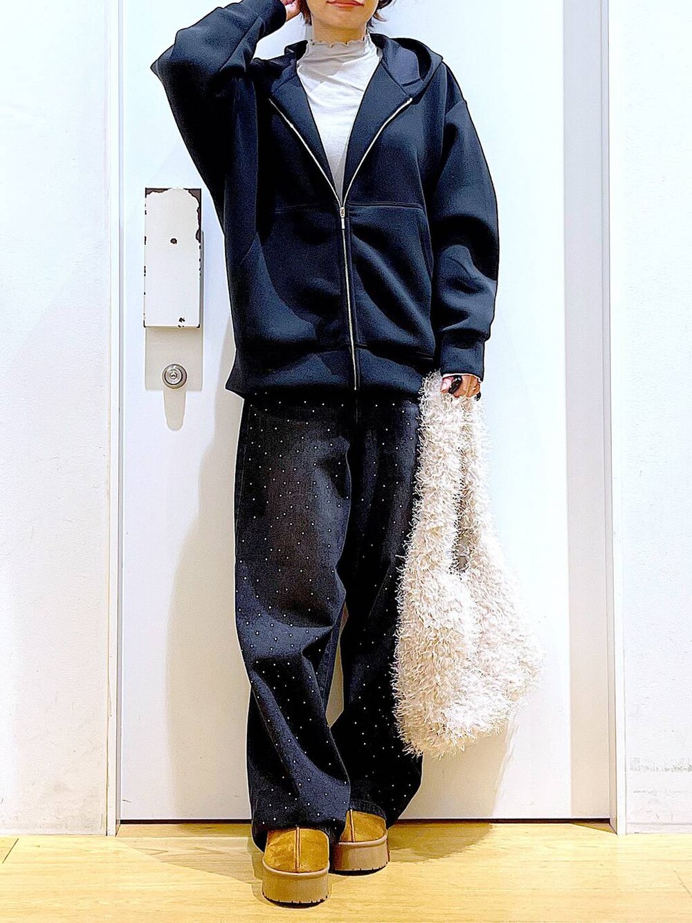 ベージュ系のスリッポン、ベージュ系のショルダーバッグ、ブラック系のデニムパンツを着用したレディースの冬コーディネートの6枚目の写真