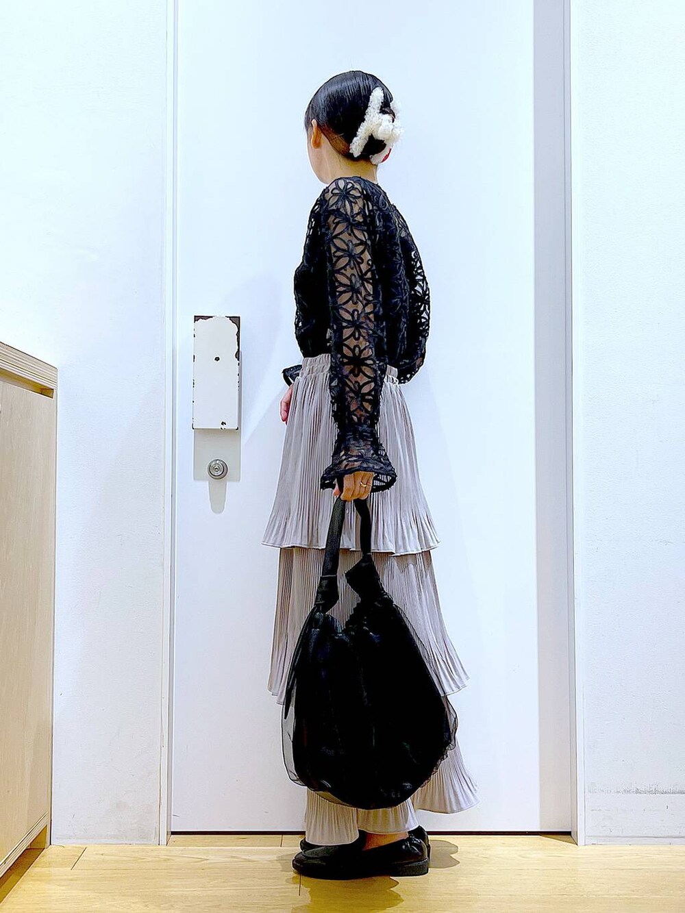 グレー系のスカート、ブラック系のトートバッグ、ブラック系のローファーを着用したレディースの秋コーディネートの3枚目の写真