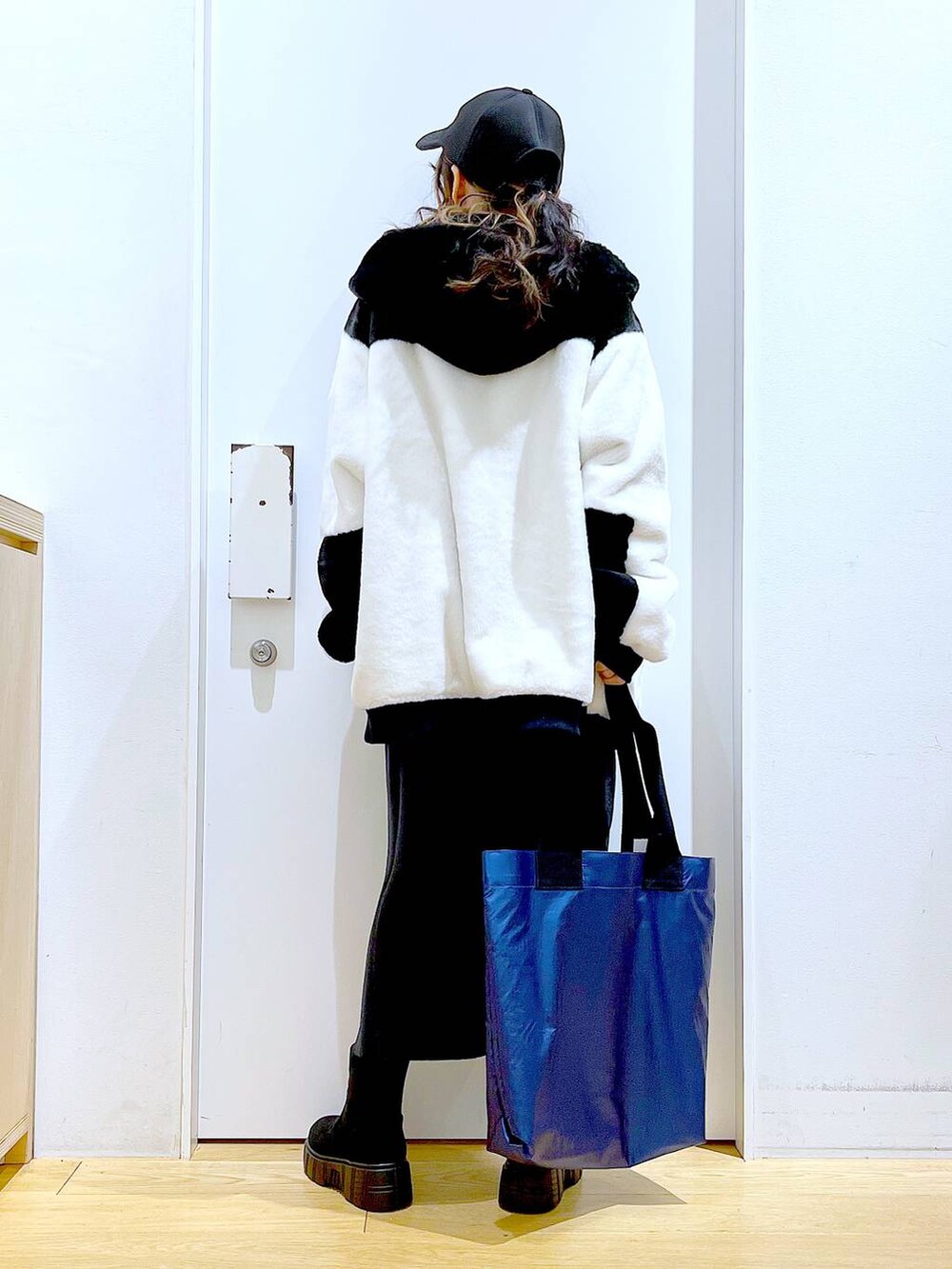 グレー系のスカート、ホワイト系のブルゾン、ブラック系のブーツを着用したレディースの冬コーディネートの5枚目の写真