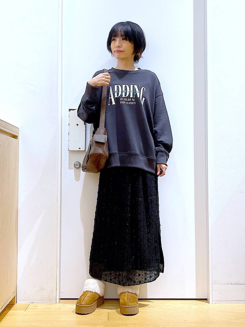 ベージュ系のスリッポン、ブラック系のスカート、グレー系のスウェットを着用したレディースの秋コーディネートの2枚目の写真