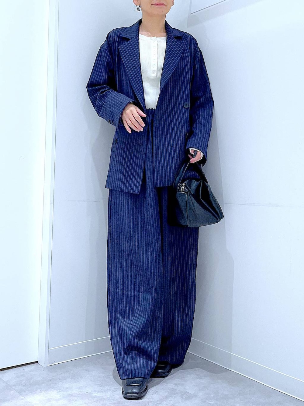 ブラック系のブーツ、ブラック系のショルダーバッグ、ブルー系のスラックスを着用したレディースの冬コーディネートの6枚目の写真