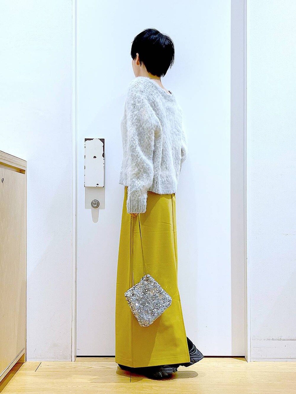 ブラック系のブーツ、イエロー系のスカート、その他のショルダーバッグを着用したレディースの冬コーディネートの3枚目の写真