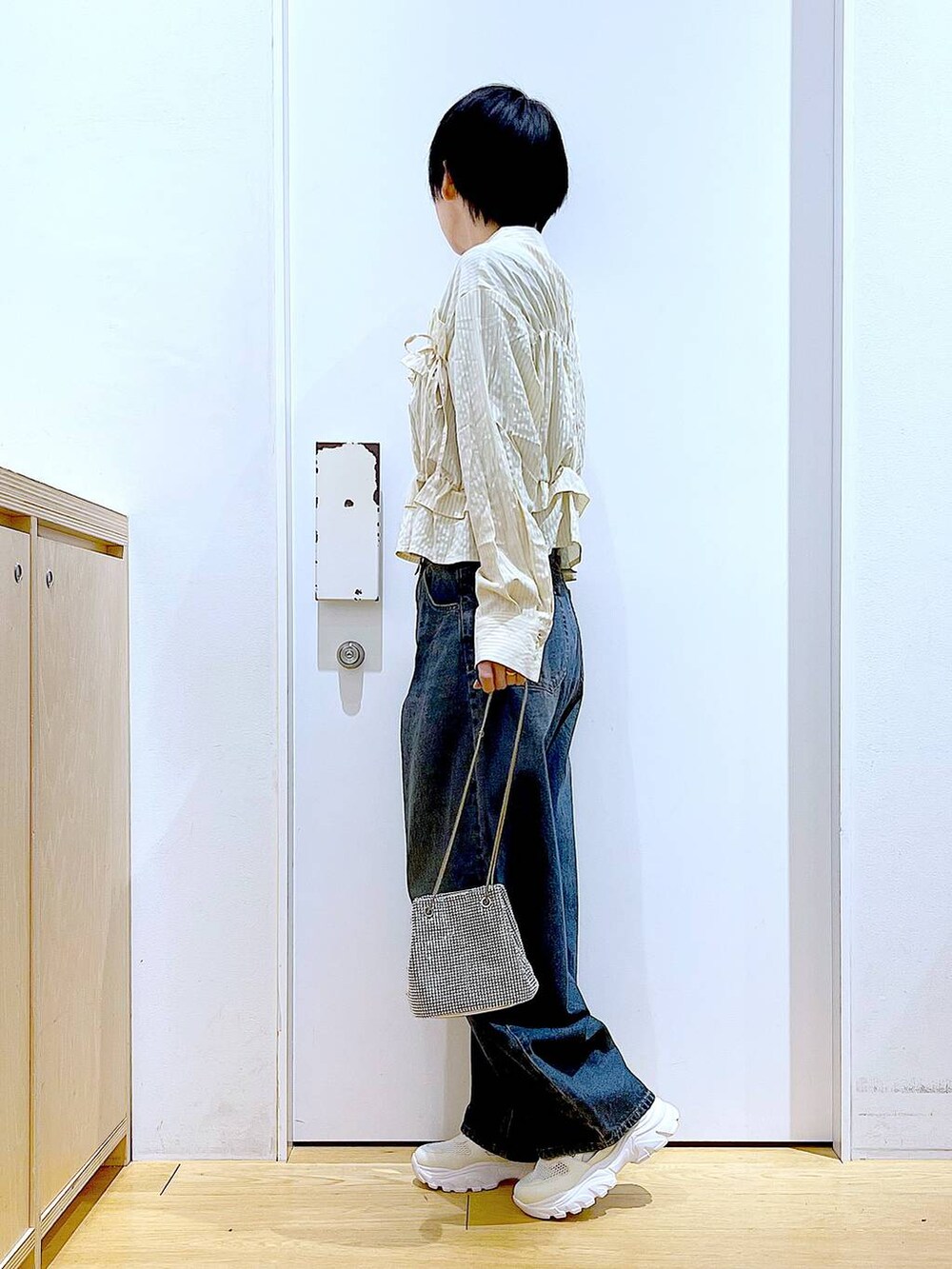 グレー系のショルダーバッグ、ブルー系のデニムパンツ、ホワイト系のスニーカーを着用したレディースの春コーディネートの3枚目の写真