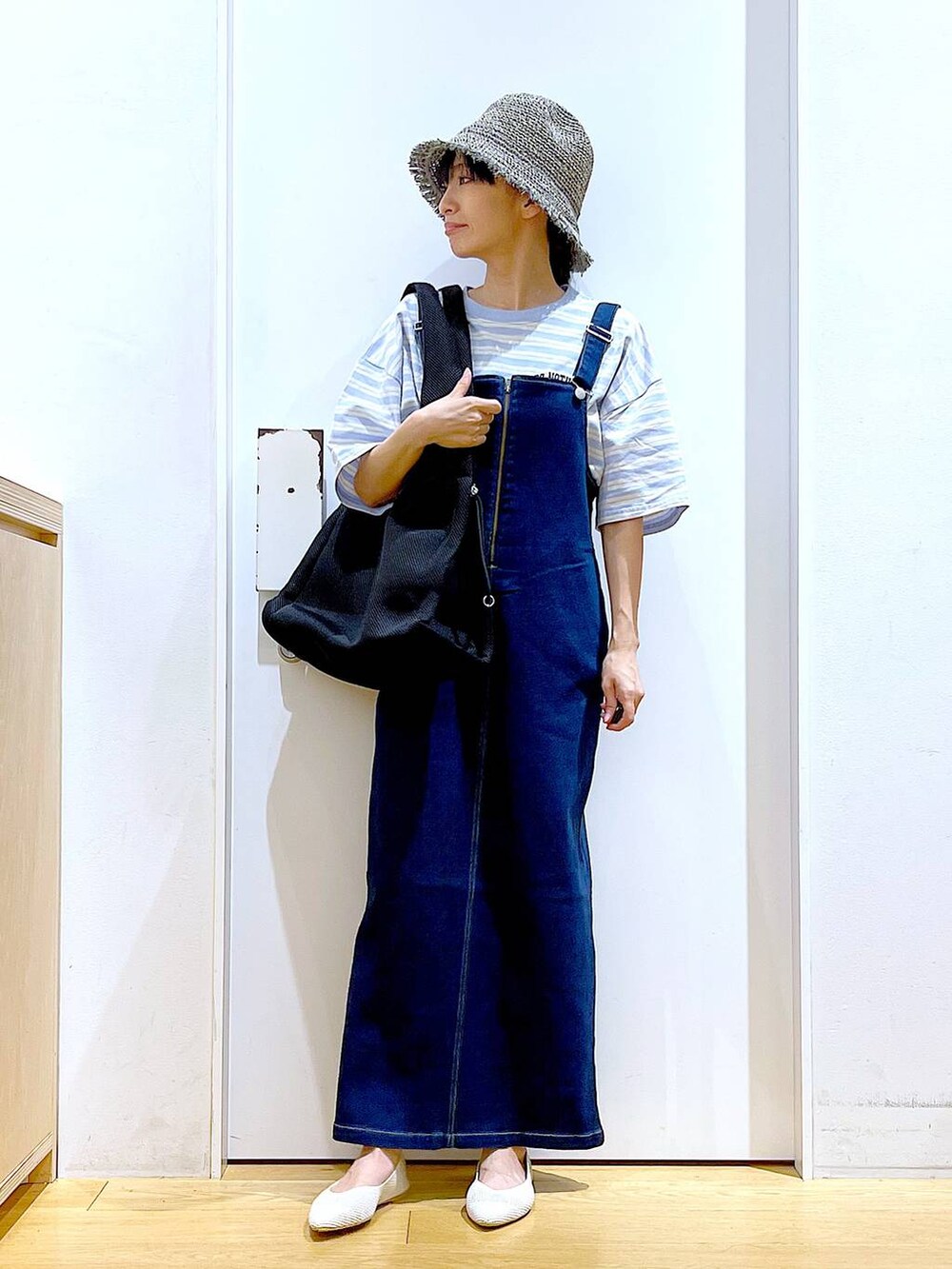 ホワイト系のパンプス、ブルー系のジャンパースカート、ブラック系のショルダーバッグを着用したレディースの夏コーディネートの2枚目の写真
