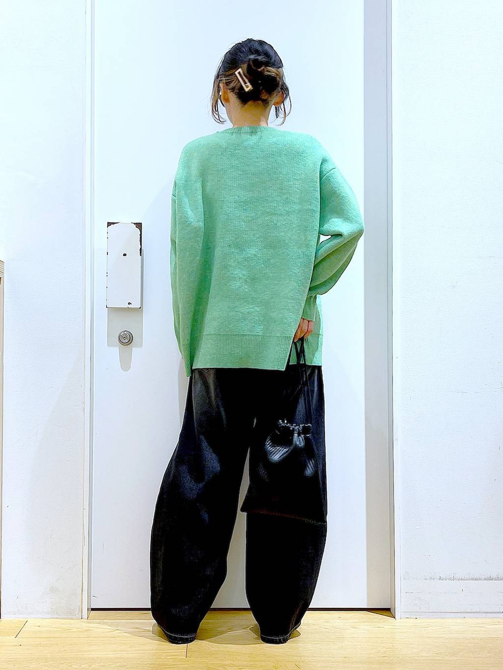 ブラック系のショルダーバッグ、ブラック系のブーツ、ブラック系のデニムパンツを着用したレディースの冬コーディネートの5枚目の写真