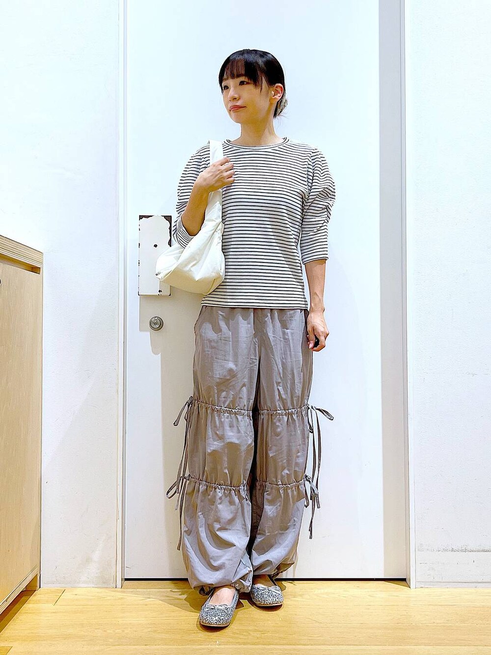 ホワイト系のハンドバッグ、シルバー系のパンプス、グレー系のその他パンツを着用したレディースの秋コーディネートの2枚目の写真