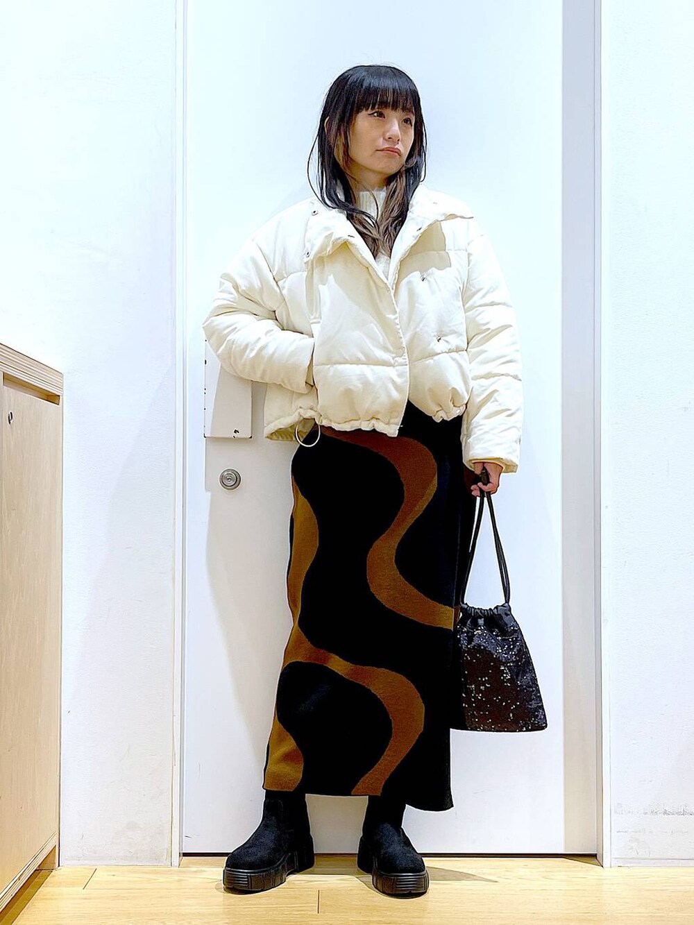 その他のスカート、ブラック系のショルダーバッグ、ブラック系のブーツを着用したレディースの冬コーディネートの2枚目の写真