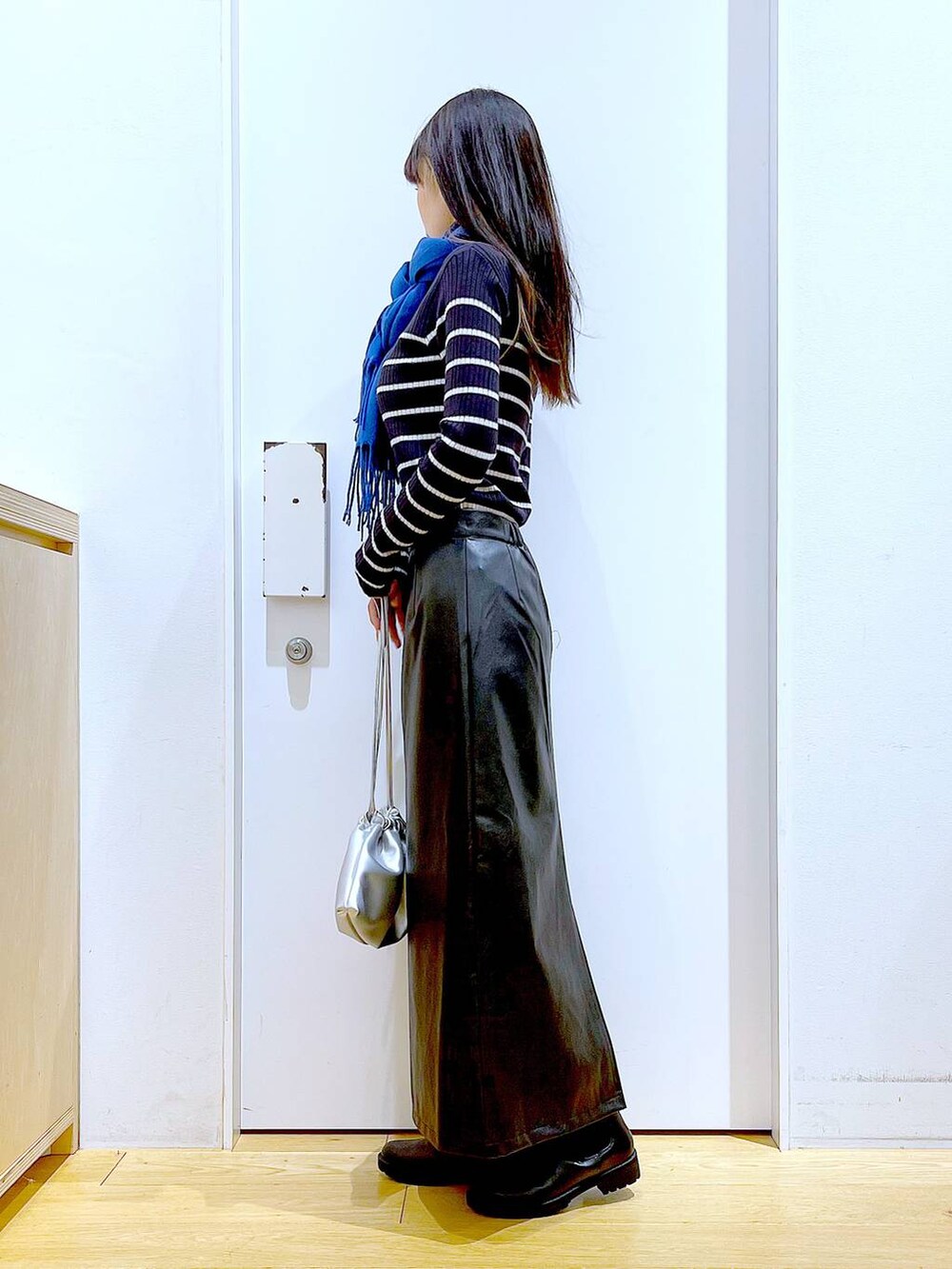 ブラック系のブーツ、ブルー系のニット/セーター、シルバー系のショルダーバッグを着用したレディースの冬コーディネートの3枚目の写真