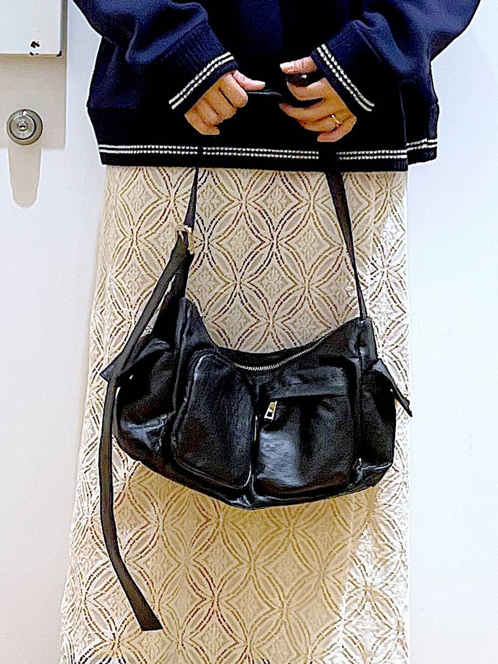 ブラック系のブーツ、ホワイト系のスカート、ブラック系のショルダーバッグを着用したレディースの冬コーディネートの9枚目の写真