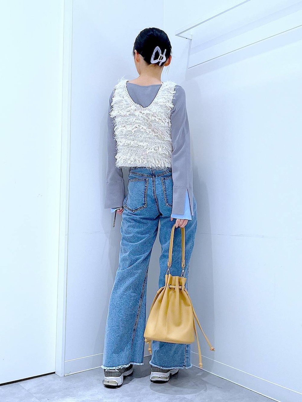 ホワイト系のベスト、グレー系のニット/セーター、ブルー系のデニムパンツを着用したレディースの春コーディネートの5枚目の写真