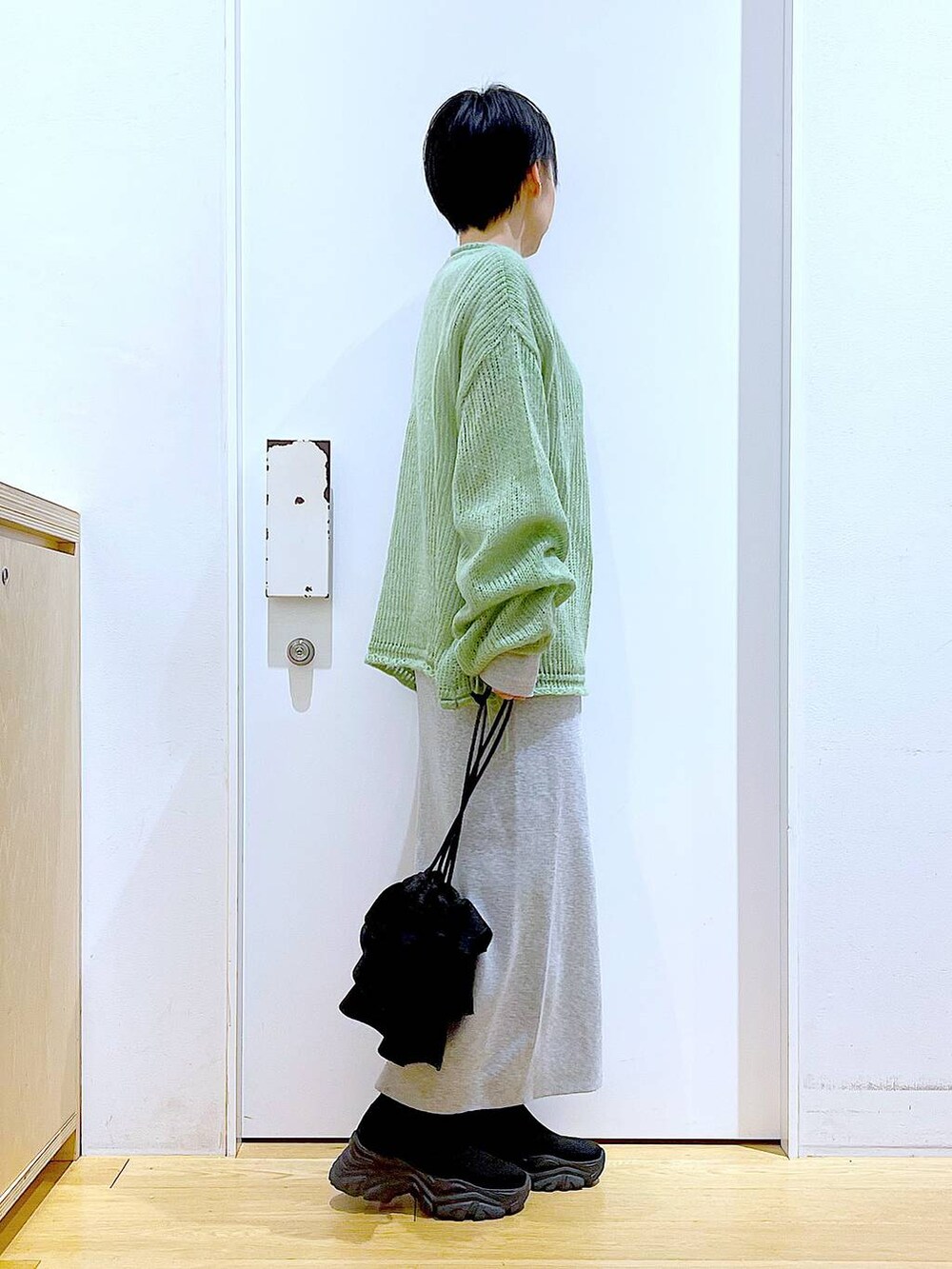 ブラック系のブーツ、グリーン系のニット/セーター、グレー系のスカートを着用したレディースの冬コーディネートの4枚目の写真