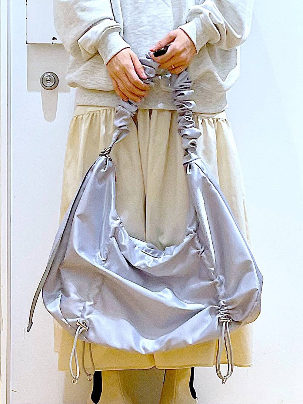 ベージュ系のスウェット、ホワイト系のスカート、ベージュ系のブーツを着用したレディースの春コーディネートの9枚目の写真