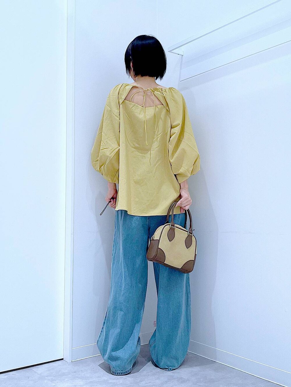 ブラック系のスニーカー、ブルー系のデニムパンツ、イエロー系のシャツ/ブラウスを着用したレディースの秋コーディネートの5枚目の写真