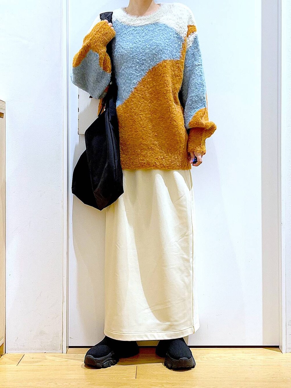 ブラック系のショルダーバッグ、ブラック系のブーツ、オレンジ系のニット/セーターを着用したレディースの冬コーディネートの6枚目の写真