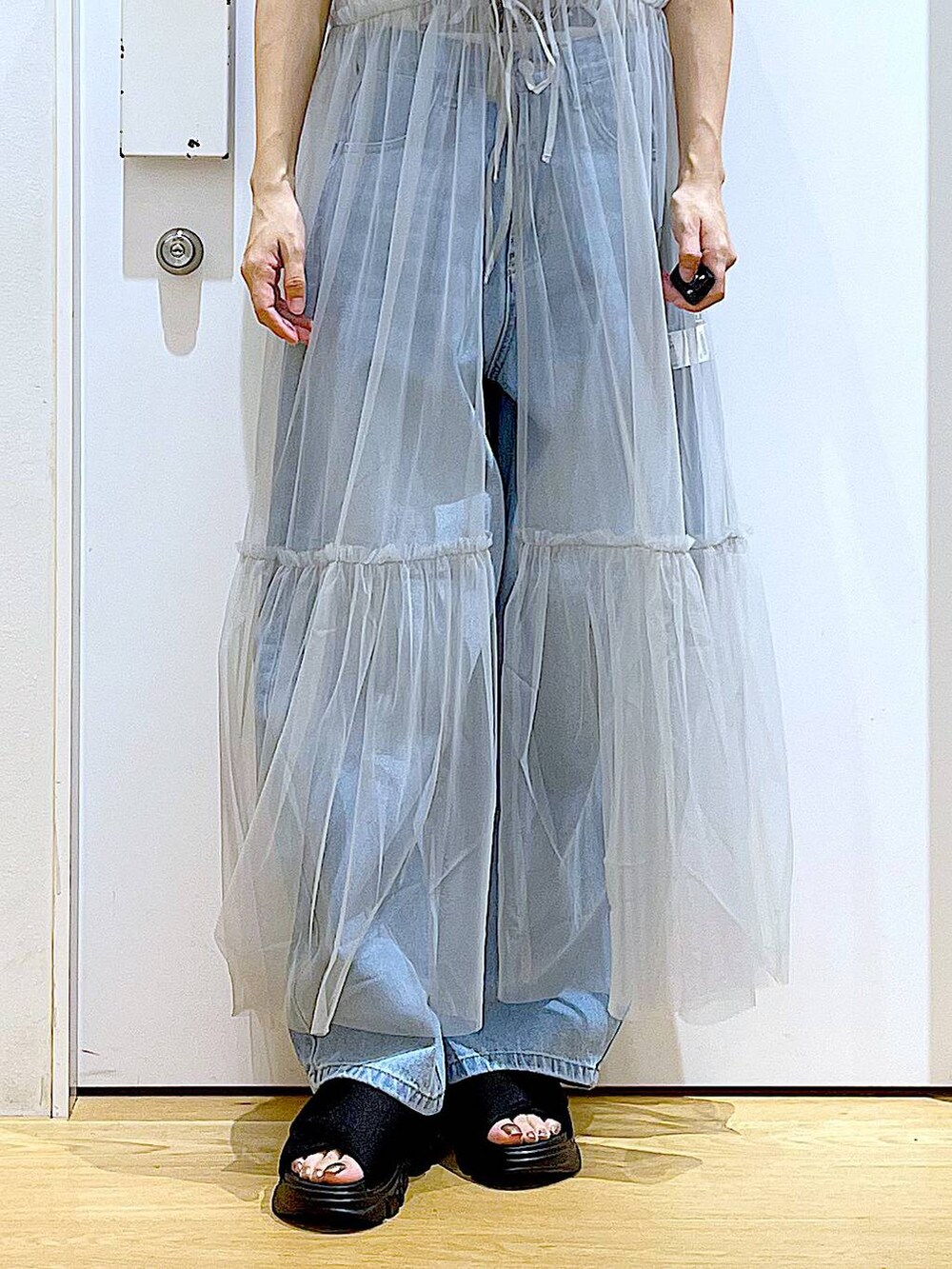 グレー系のワンピース、ブルー系のデニムパンツ、ブラック系のショルダーバッグを着用したレディースの夏コーディネートの8枚目の写真