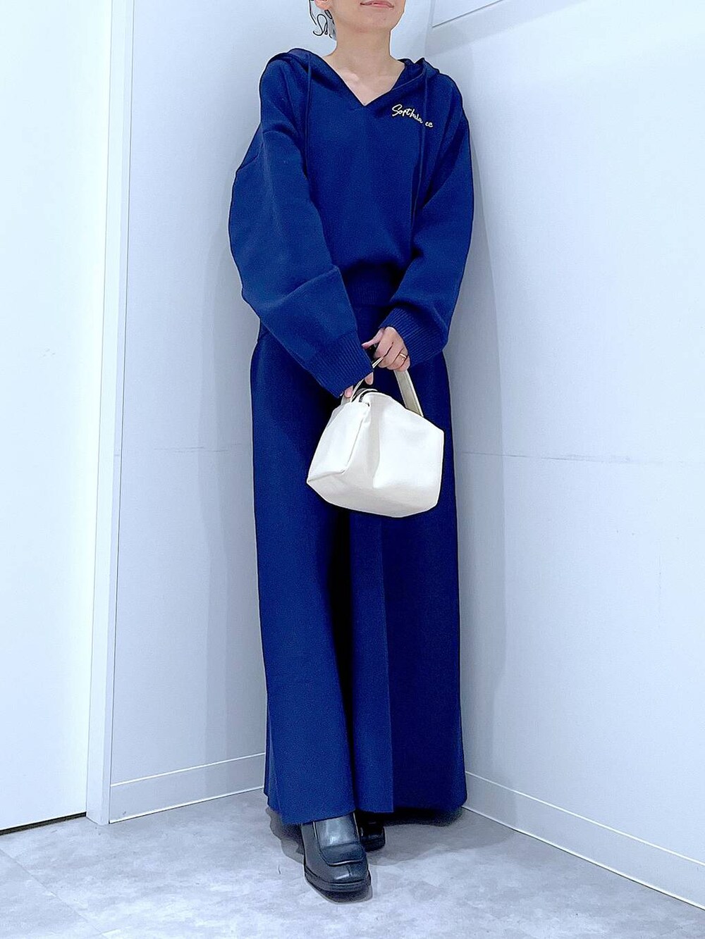 ブラック系のブーツ、ホワイト系のショルダーバッグ、ブルー系のスカートを着用したレディースの冬コーディネートの6枚目の写真