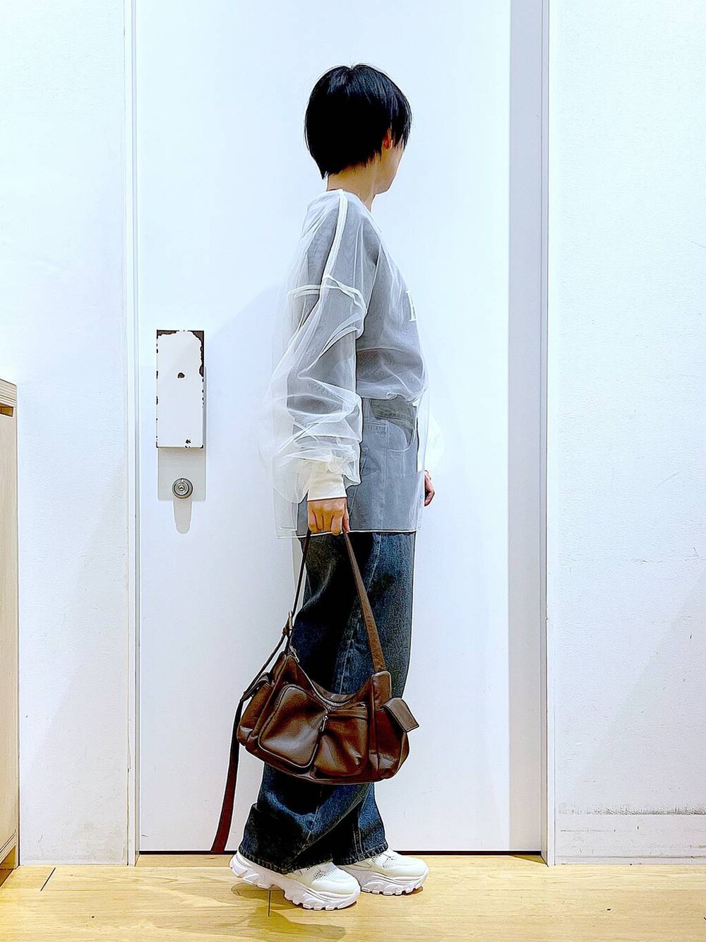 ブルー系のデニムパンツ、ブラウン系のショルダーバッグ、ホワイト系のスニーカーを着用したレディースの春コーディネートの4枚目の写真