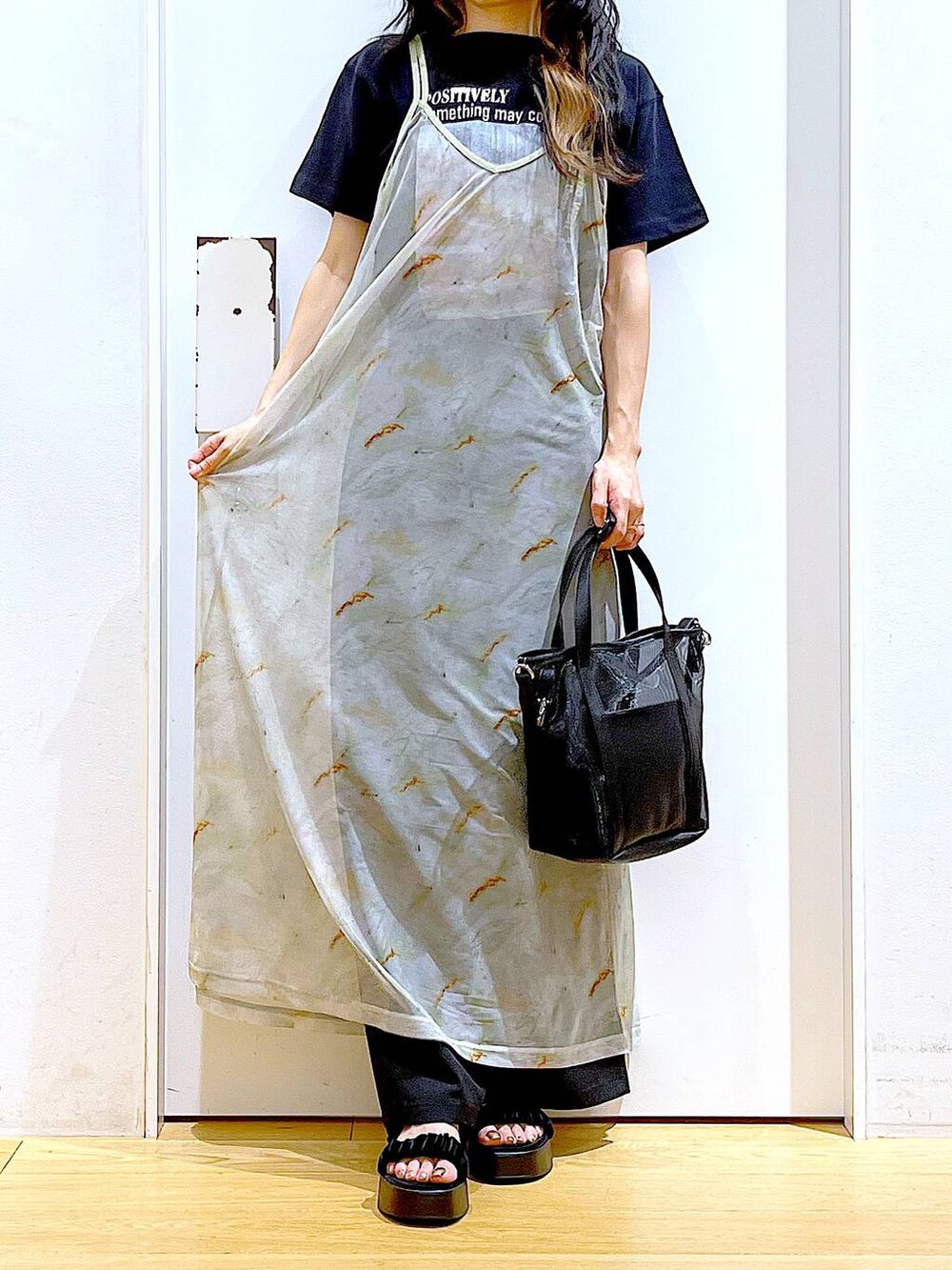 ブラック系のサンダル、ブラック系のトートバッグ、ベージュ系のワンピースを着用したレディースの夏コーディネートの6枚目の写真