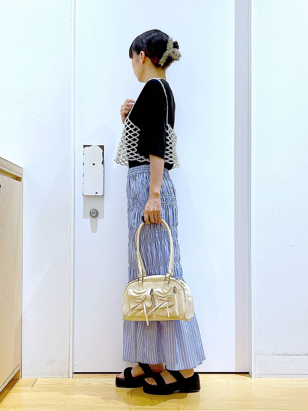 ブラック系のサンダル、ホワイト系のベスト、その他のスカートを着用したレディースの夏コーディネートの3枚目の写真