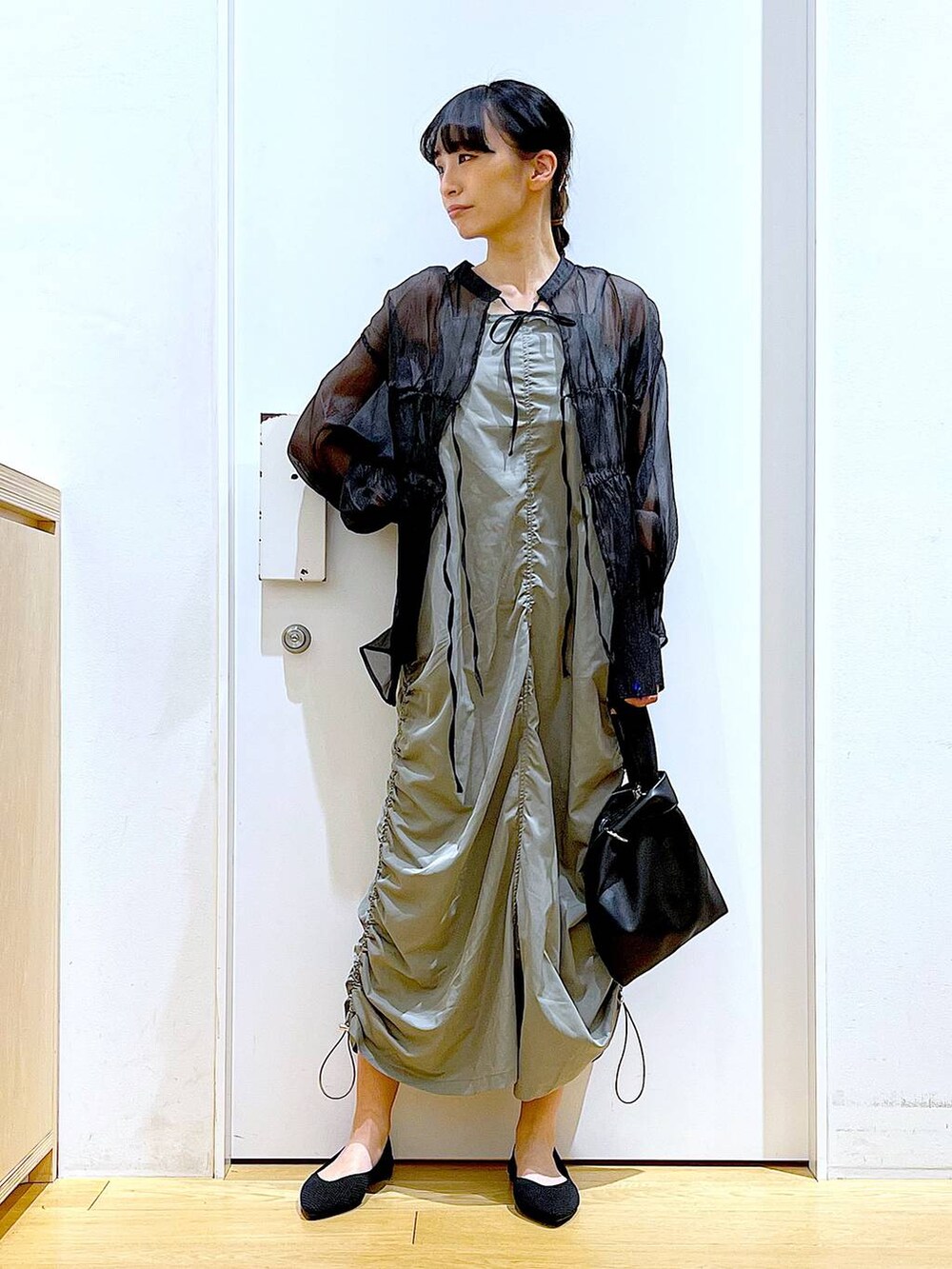 ブラック系のショルダーバッグ、ブラック系のパンプス、グリーン系のワンピースを着用したレディースの春コーディネートの2枚目の写真