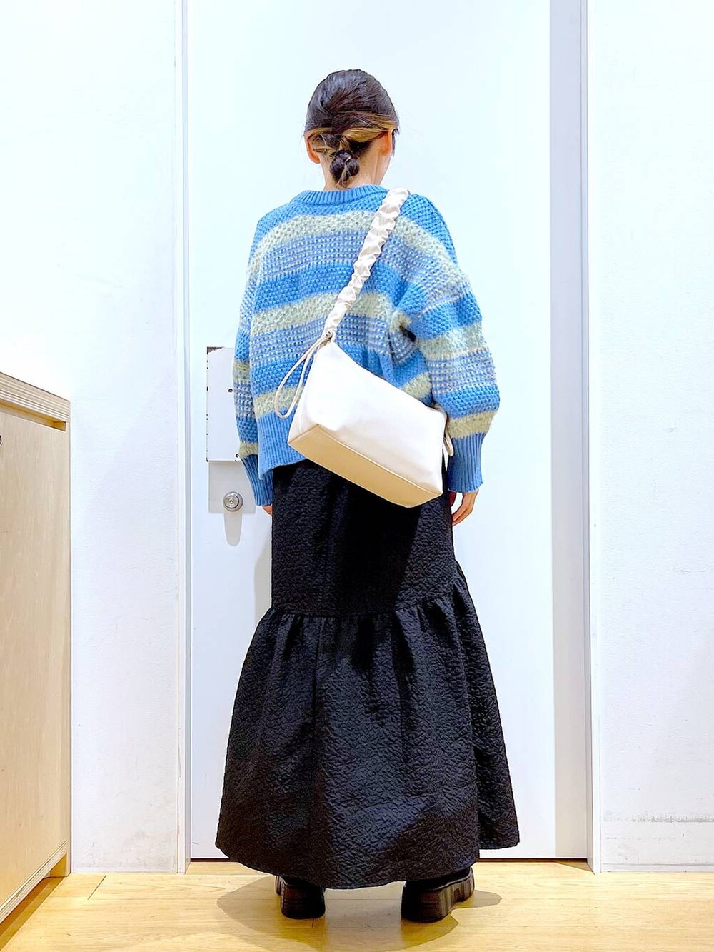 ホワイト系のショルダーバッグ、ブラック系のブーツ、ブラック系のスカートを着用したレディースの冬コーディネートの5枚目の写真