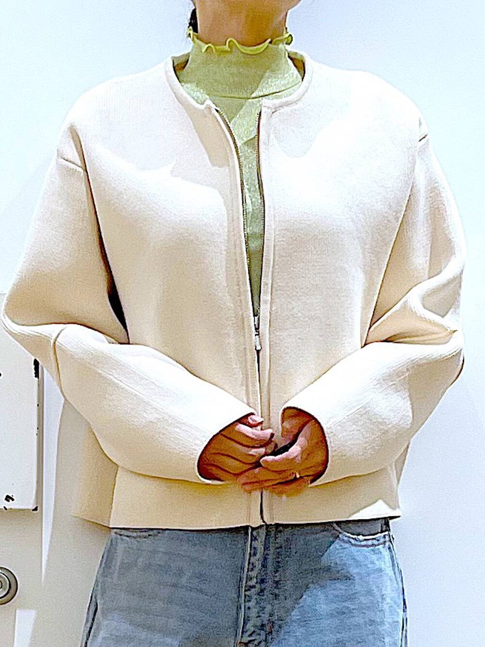 グリーン系のTシャツ/カットソー、ベージュ系のスニーカー、ブルー系のデニムパンツを着用したレディースの冬コーディネートの7枚目の写真