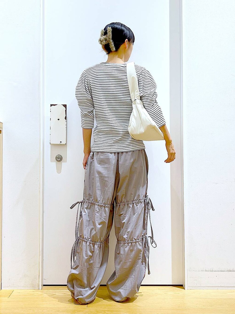 ホワイト系のハンドバッグ、シルバー系のパンプス、グレー系のその他パンツを着用したレディースの秋コーディネートの5枚目の写真