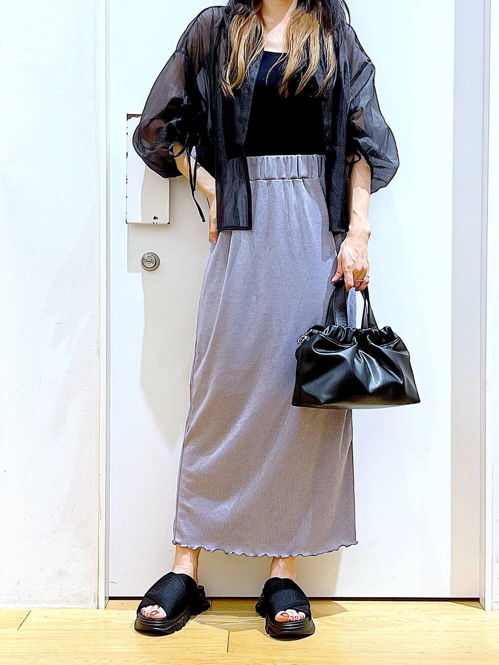 パープル系のスカート、ブラック系のサンダル、ブラック系のニット/セーターを着用したレディースの夏コーディネートの6枚目の写真