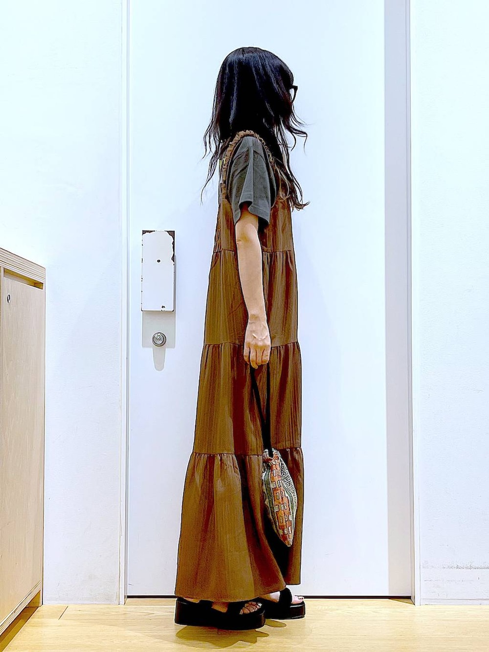 ブラウン系のショルダーバッグ、ブラック系のサンダル、グレー系のTシャツ/カットソーを着用したレディースの夏コーディネートの4枚目の写真